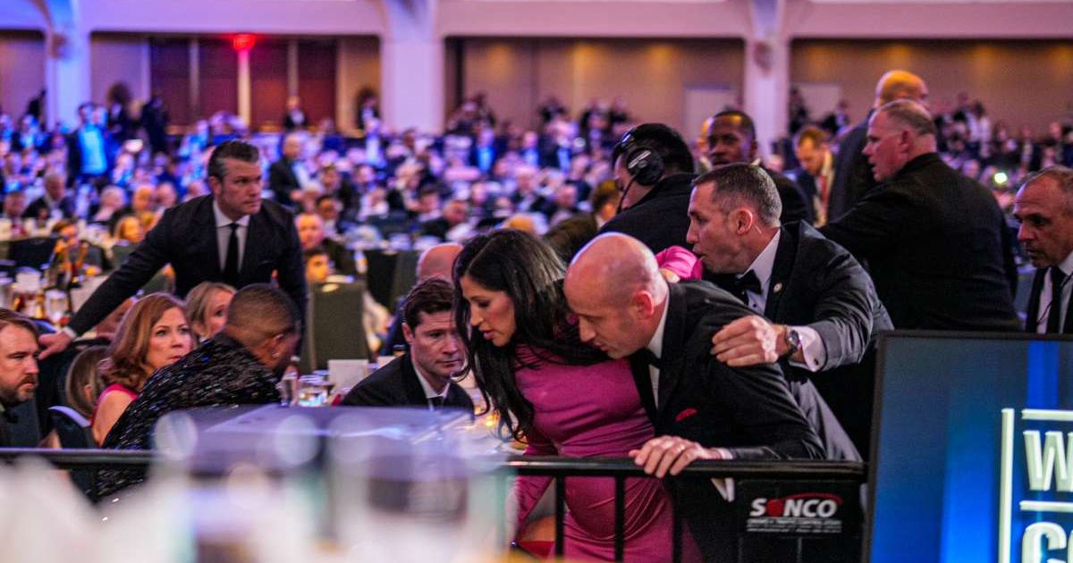 Secretary of War Pete Hegseth (L) stands as White House Deputy Chief of Staff for Policy Stephen Miller and his wife Katie Miller (C) are taken out of the ballroom by security agents during a shooting incident at the annual White House Correspondents Asso