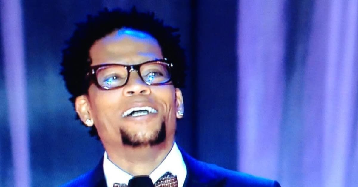 Comedian DL Hughley speaking on stage. (Cover Image Source: Facebook | D.L. Hughley)