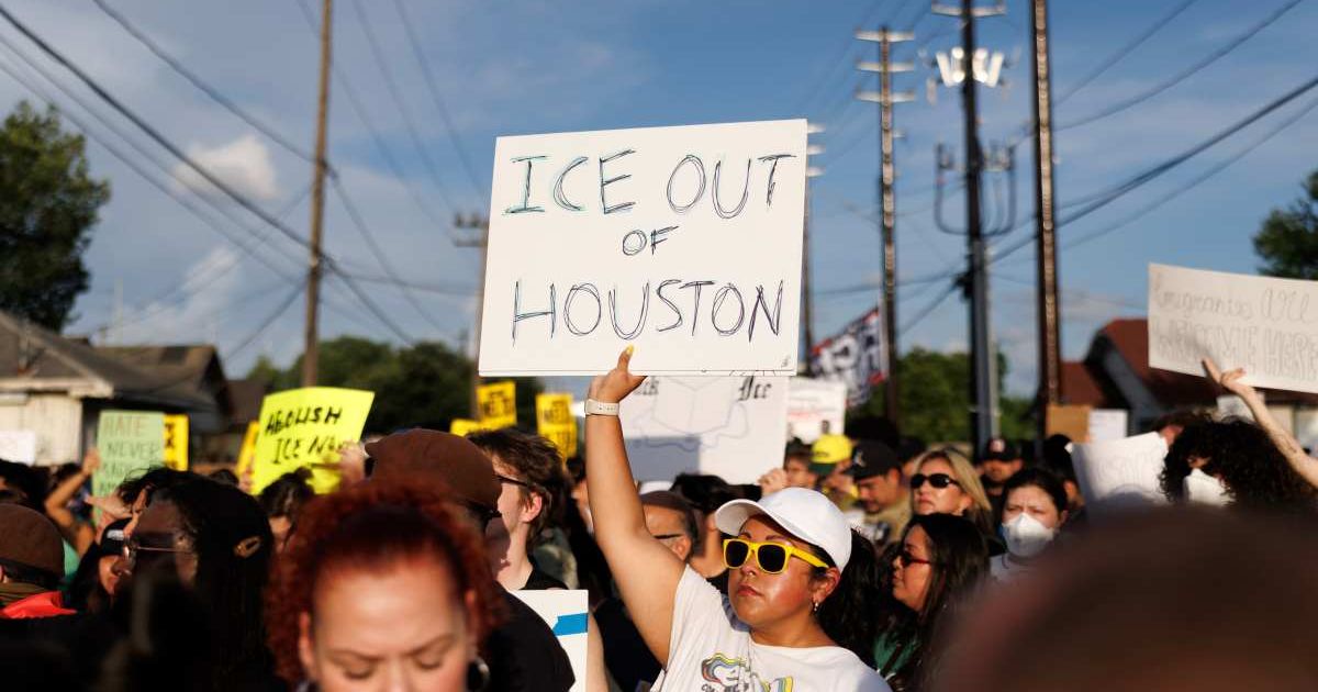 A woman holds a sign reading "ICE OUT OF HOUSTON" during a vigil for Lorenzo Salgado Araujo, a Mexican national fatally shot by a federal immigration agent (Cover Image Source: AP Photo | Photo by Mark Felix)