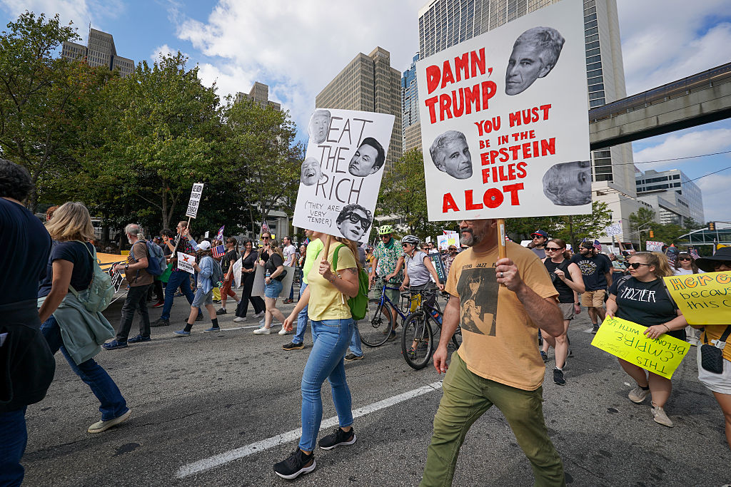 Demonstrators hold protest signs during a march from the Atlanta Civic Center to the Georgia State Capitol on October 18, 2025 in Atlanta, Georgia. (Image source: Getty Images/Photo by Julia Beverly/Getty Images)
