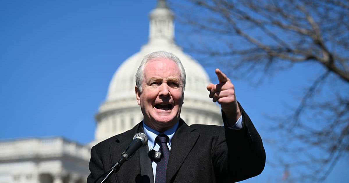 Senator Chris Van Hollen (D-MD) speaks in front of a memorial (Cover Image Source: Getty Images | Photo by Matt McClain)